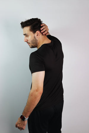 A man wearing an Athlix black performance tee against a light studio background.