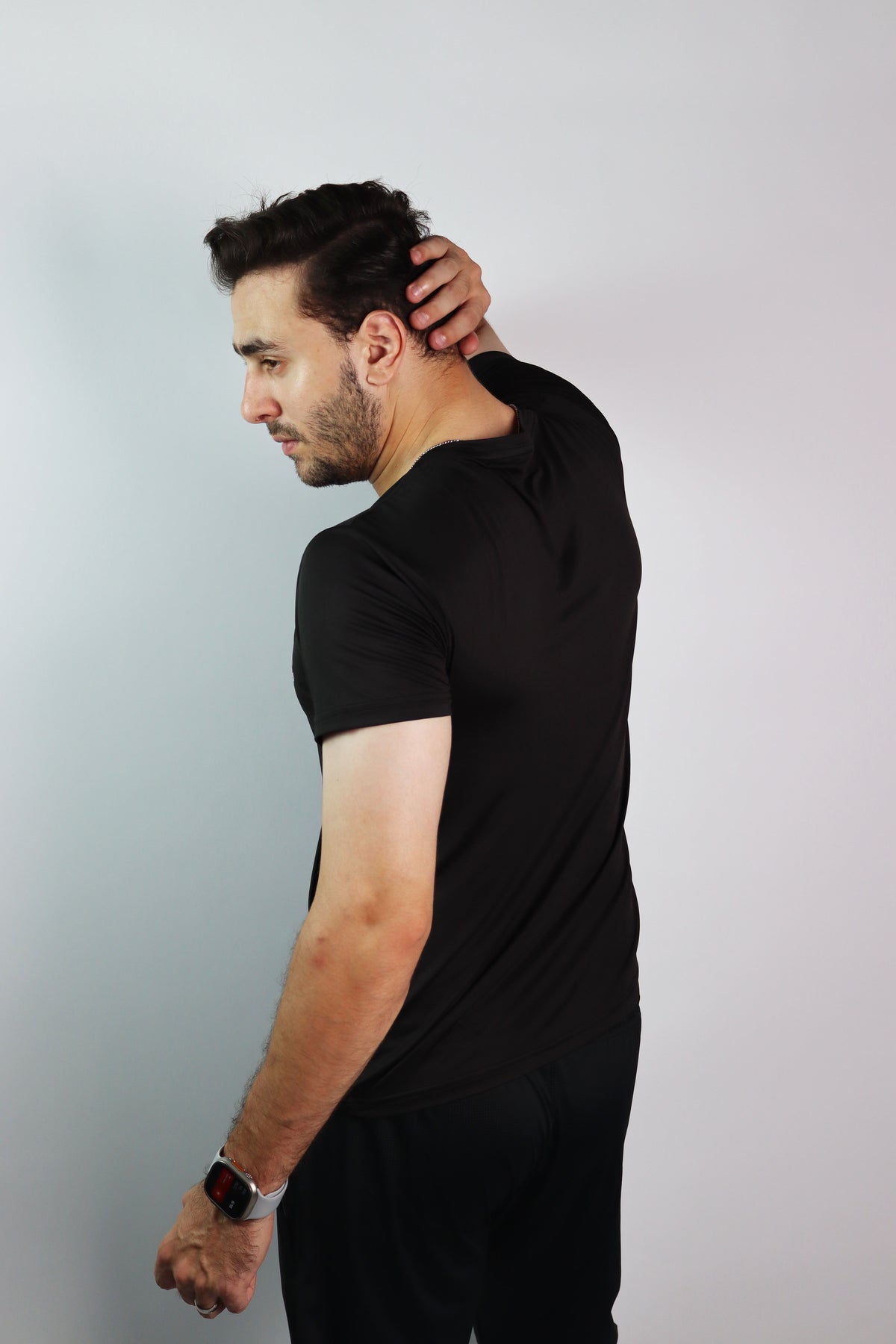 A man wearing an Athlix black performance tee against a light studio background.