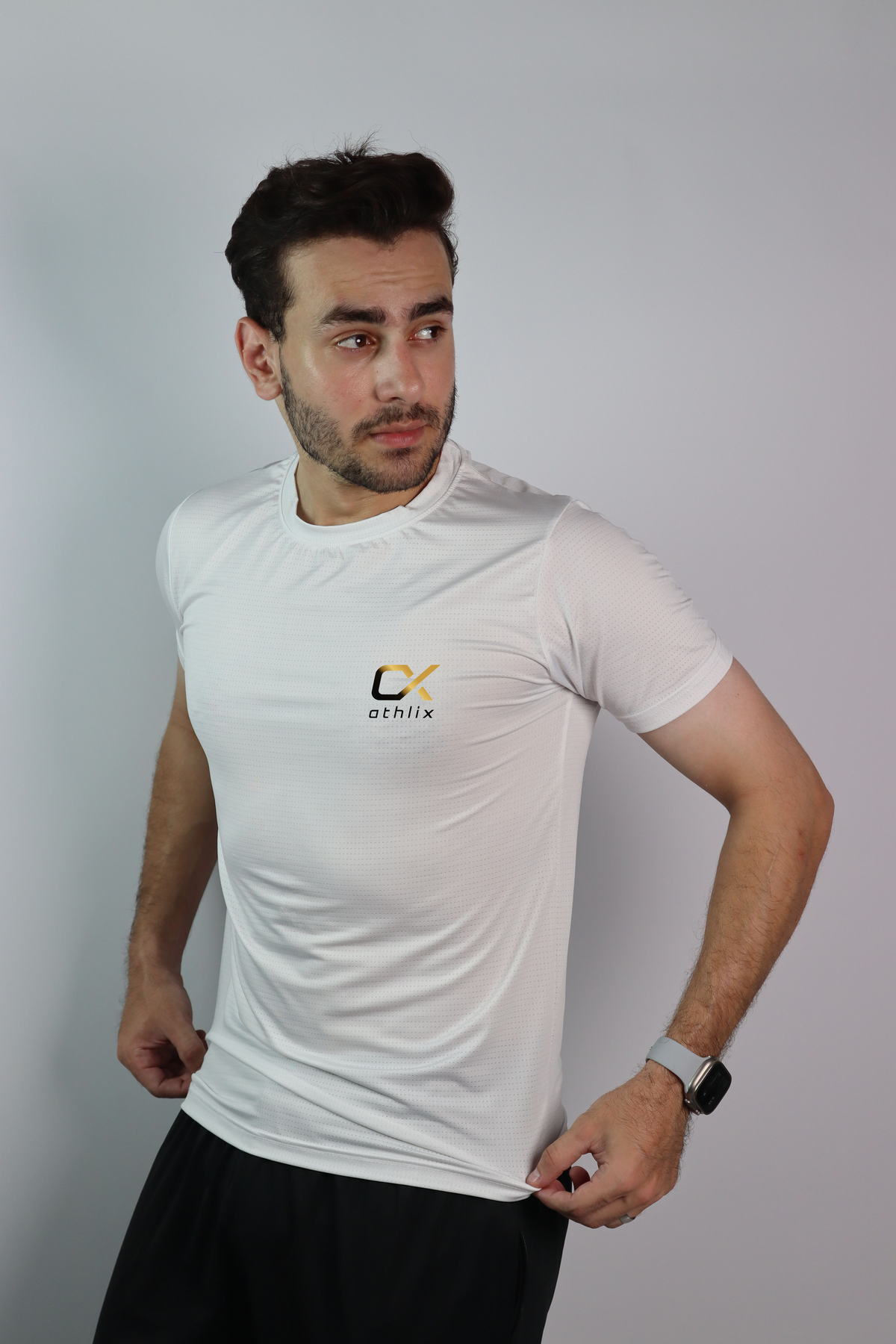 A man wearing an Athlix white performance tee against a light studio background.